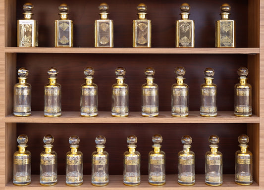 Collection of antique perfume bottles on wooden shelves.